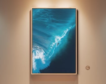 Könnte beinhalten: Gerahmter Druck eines Surfers auf einer großen Ozeanwelle. Das Bild zeigt die türkisen und weißen Farben der Welle, wobei der Surfer klein erscheint. Das Kunstwerk wird an einer beigen Wand mit Holzrahmen gezeigt.