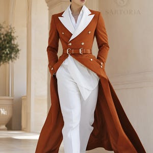 May include: A long, double-breasted rust-orange coat with wide white lapels, worn over a white shirt and white trousers. The coat features gold buttons and a matching rust-orange belt at the waist. The text SARTORIA is visible in the upper right corner.