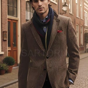 Puede incluir: Chaqueta de tweed marrón con bufanda azul marino y pañuelo rojo. La chaqueta tiene un patrón de espiga clásico y se lleva sobre una camisa a rayas. El conjunto es elegante y sofisticado.