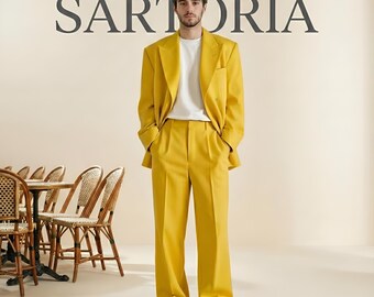 May include: A bright yellow suit consisting of a double-breasted blazer and matching wide-leg trousers, worn over a plain white t-shirt. The word SARTORIA is printed in large dark gray capital letters on the wall behind the suit.
