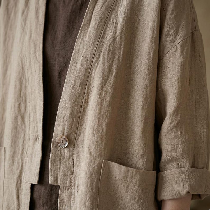 Pu&ograve; includere: Giacca in lino beige dalla vestibilit&agrave; morbida, con chiusura a un solo bottone e due tasche frontali. Le maniche sono arrotolate e la giacca &egrave; sovrapposta a un top marrone. Il tessuto ha un aspetto strutturato.