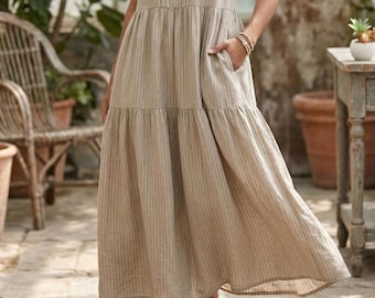 May include: A sleeveless midi dress in a light beige color featuring thin vertical dark stripes. The dress has a tiered skirt design with a gathered waistline and side pockets, crafted from a textured fabric with a visible weave pattern.