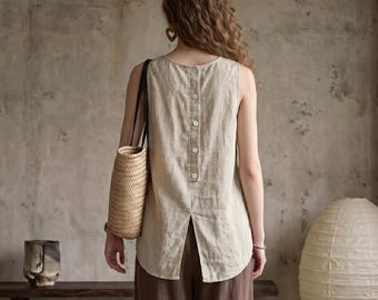 May include: A sleeveless beige linen top featuring a vertical row of five light-colored buttons down the center back and a split hem. The top is paired with dark brown trousers and a woven straw shoulder bag with black leather straps.