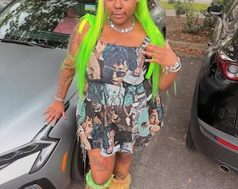 May include: A woman in a tapestry mini dress featuring a collage of faces, complemented by neon green hair and fur-lined boots. The dress has a square neckline and thin straps. The boots are light brown.