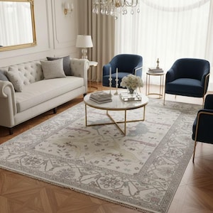 Puede incluir: Un salón amueblado con un sofá crema, sillones azul marino y una mesa de centro de mármol. Una alfombra estampada en tonos neutros cubre el suelo. La habitación está decorada con lámparas, un espejo y una lámpara de araña.