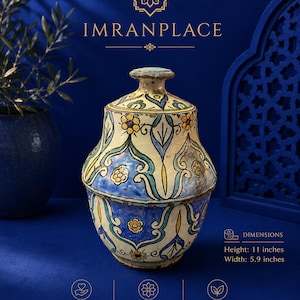Puede incluir: Una pieza artesanal marroquí vintage hecha a mano. Este tarro de cerámica único y único, con tapa, está adornado con patrones florales y geométricos en azul, amarillo y blanco. El tarro mide 28 cm de alto y 15 cm de ancho.