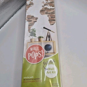Puede incluir: Un kit de arte mural Wall Pops Super Wall Art Kit con un diseño de mapa del mundo de pared de ladrillo. El empaque incluye el texto peel, stick + move, Wall Pops y Super Wall Art Kit. Las dimensiones son 60,96 cm x 91,44 cm en el empaque.