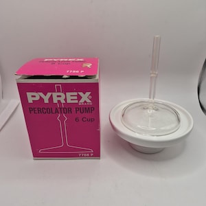 Può includere: Una pompa per percolatore marca Pyrex per caffettiera da 6 tazze, dotata di stelo e base in vetro trasparente, accompagnata dalla scatola originale in cartone rosa e bianco con il testo Pyrex Percolator Pump 6 Cup e il numero 7756 P.