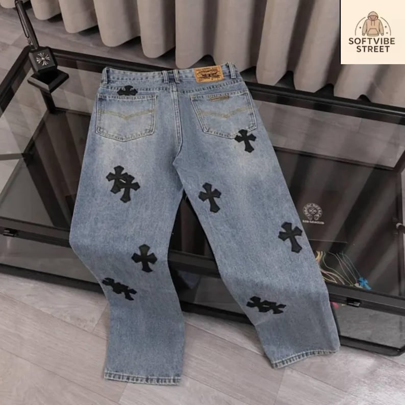 May include: Light blue denim jeans with black cross appliques. The jeans have a classic five-pocket design and a straight leg fit. The back features a leather patch. The brand name "SOFTVIBE STREET" is visible in the upper right corner.