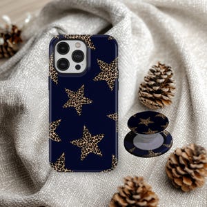 May include: A navy blue phone case and matching phone grip featuring a repeating pattern of leopard print stars. The phone case is designed to fit a smartphone. The phone grip is round and expandable.