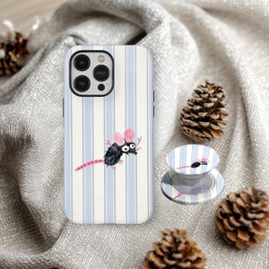 Op de afbeelding: Een telefoonhoesje en telefoonhouder met een cartoon muisontwerp. De hoes heeft een verticaal gestreept patroon in lichtblauw en wit. De muis is zwart met roze oren en een roze staart.