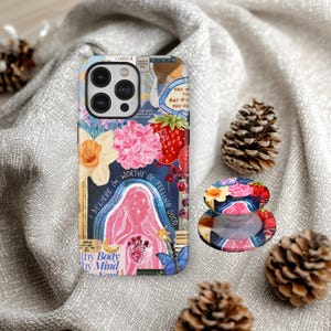 May include: A phone case and phone grip with a vibrant floral and motivational design. The case displays a pink figure, strawberries, and the text "I BELIEVE I'M WORTHY OF FEELING GOOD". The phone grip has a matching design.