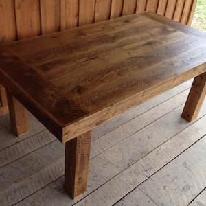 Puede incluir: Una mesa de madera r&uacute;stica con un acabado de madera natural y una tapa rectangular. La mesa tiene cuatro patas y est&aacute; hecha de madera reciclada.