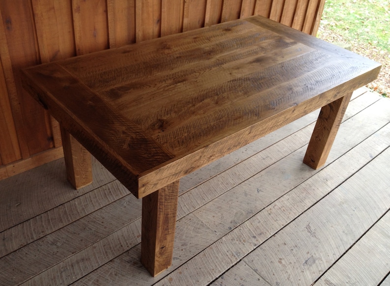 Puede incluir: Una mesa de madera r&uacute;stica con un acabado de madera natural y una tapa rectangular. La mesa tiene cuatro patas y est&aacute; hecha de madera reciclada.