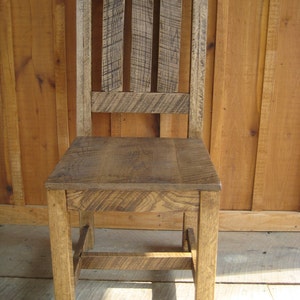 Puede incluir: Una silla de madera r&uacute;stica con respaldo de listones y un dise&ntilde;o sencillo. La silla est&aacute; hecha de madera reciclada y tiene un acabado natural.