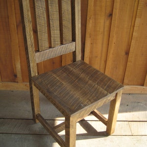 Puede incluir: Una silla de madera r&uacute;stica con respaldo de listones y acabado marr&oacute;n oscuro. La silla tiene un dise&ntilde;o sencillo y est&aacute; hecha de madera reciclada.
