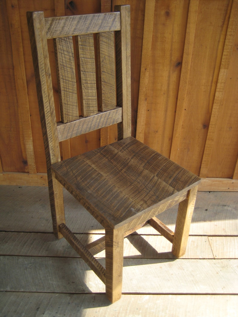 Puede incluir: Una silla de madera r&uacute;stica con respaldo de listones y acabado marr&oacute;n oscuro. La silla tiene un dise&ntilde;o sencillo y est&aacute; hecha de madera reciclada.
