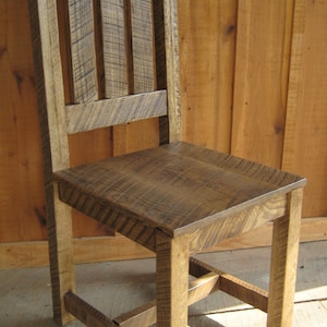 Puede incluir: Una silla de madera r&uacute;stica con respaldo de listones y asiento de madera maciza. La silla tiene un estilo sencillo de granja y est&aacute; hecha de madera recuperada.