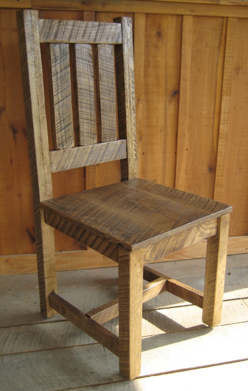 Puede incluir: Una silla de madera r&uacute;stica con respaldo de listones y asiento de madera maciza. La silla tiene un estilo sencillo de granja y est&aacute; hecha de madera recuperada.