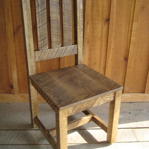 Puede incluir: Una silla de madera r&uacute;stica con respaldo de listones y acabado desgastado. La silla tiene un dise&ntilde;o sencillo con un asiento rectangular y cuatro patas.
