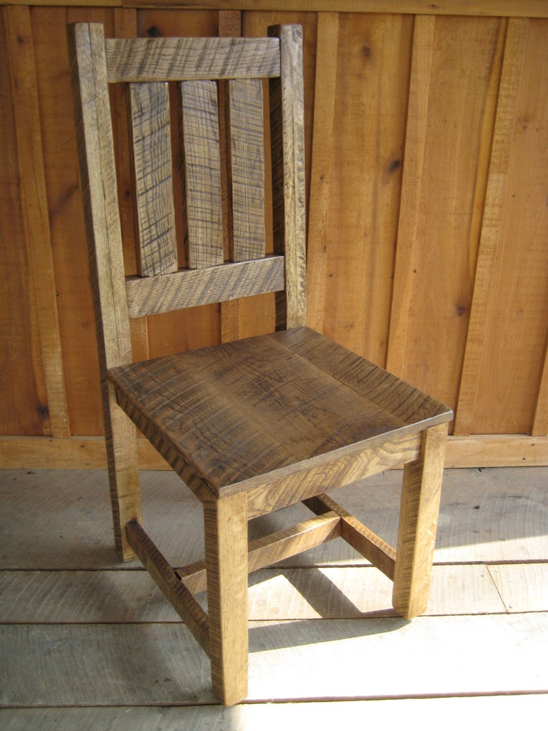 Puede incluir: Una silla de madera r&uacute;stica con respaldo de listones y acabado desgastado. La silla tiene un dise&ntilde;o sencillo con un asiento rectangular y cuatro patas.