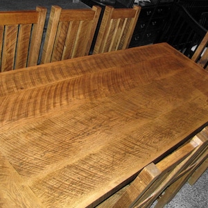 Puede incluir: Una gran mesa de comedor de madera r&uacute;stica con un acabado de madera natural. La mesa est&aacute; rodeada de seis sillas con un acabado de madera similar. La superficie de la mesa tiene un patr&oacute;n de veta &uacute;nico.