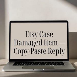 Puede incluir: Un portátil plateado que muestra el texto "Etsy Case Damaged Item - Copy/Paste Reply" en negro. El portátil está abierto sobre una superficie clara, con un fondo neutro.