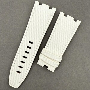 May include: Two-piece white watch strap with a textured surface. The strap has a rectangular shape with rounded edges and a series of holes for adjustment. The stitching is white, and the strap is designed to attach to a watch face.
