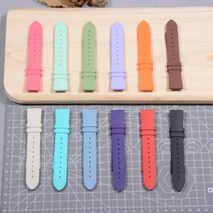 May include: A collection of colorful watch straps in various shades, including pink, mint green, and orange. The straps are made of a flexible material and feature multiple holes for adjustment. The image shows a variety of colors and styles.
