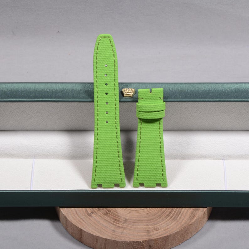 Puede incluir: Juego de correas de reloj verde brillante. Las correas est&aacute;n hechas de un material texturizado y presentan costuras en contraste. El juego incluye dos piezas, una con varios agujeros para ajuste y otra con una hebilla. Las correas se muestran dentro de una caja verde.