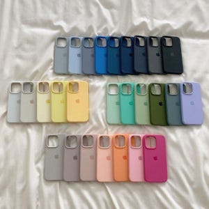 Könnte beinhalten: Eine Sammlung von Smartphone-Hüllen aus Silikon, angeordnet in drei Reihen, mit einem breiten Farbspektrum, darunter Blau-, Grün-, Gelb-, Rosa- und Neutraltöne. Jede Hülle hat einen quadratischen Kameraausschnitt und ein Apple-Logo.