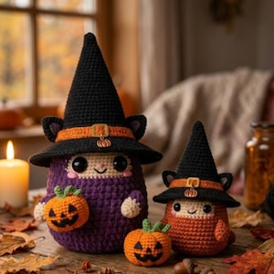 May include: Two crocheted plush figures wearing black witch hats with orange bands and small pumpkin charms. The larger figure is purple and holds a small orange jack-o'-lantern, while the smaller figure is orange and stands next to one.