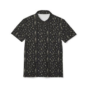 May include: Black polo shirt with a repeating pattern of skeletons, skulls, and golf-themed elements in beige. The shirt has short sleeves and a white collar.