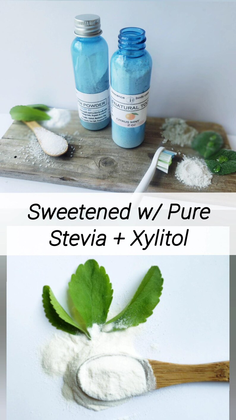 May include: Two blue bottles of tooth powder and a toothbrush are displayed on a wooden surface. The bottles have white labels. The text "Sweetened w/ Pure Stevia + Xylitol" is also visible. A wooden spoon holds a white powder.