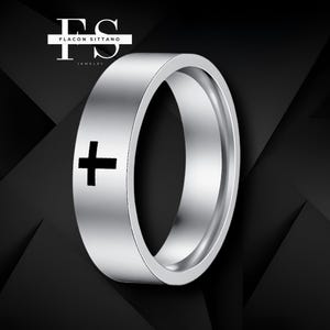 Könnte beinhalten: Ein silberfarbener Ring mit einem schwarzen Kreuz auf der Seite. Der Ring hat ein flaches Band und eine polierte Oberfläche. Der Markenname "Flacon Sittano Jewelry" ist oben links zu sehen.