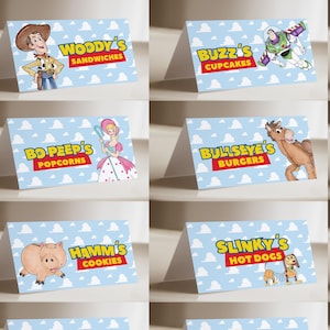 May include: A set of twelve folded paper food labels featuring Toy Story characters. Each label has a light blue background with white clouds and displays a character with their name and a food item, including Woody, Buzz, Jessie, Bo Peep, Bullseye, Rex, Hamm, Slinky, Aliens, Mr. Potato Head, Forky, and Lotso.