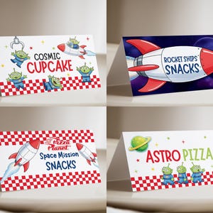 May include: Four folded paper food tent cards featuring space-themed graphics. Designs include green three-eyed aliens, red and white rockets, and checkered patterns. Text reads Cosmic Cupcake, Rocket Ships Snacks, Space Mission Snacks, and Astro Pizza.