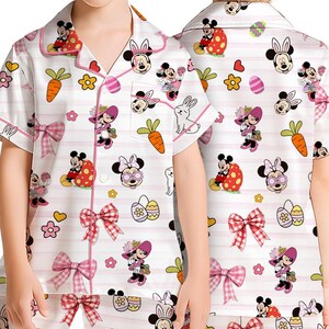 Puede incluir: Conjunto de pijama blanco para ni&ntilde;os con dise&ntilde;os de Mickey y Minnie Mouse con tem&aacute;tica de Pascua. La camiseta de manga corta y los pantalones cortos presentan detalles rosas, lazos, zanahorias y huevos de Pascua.