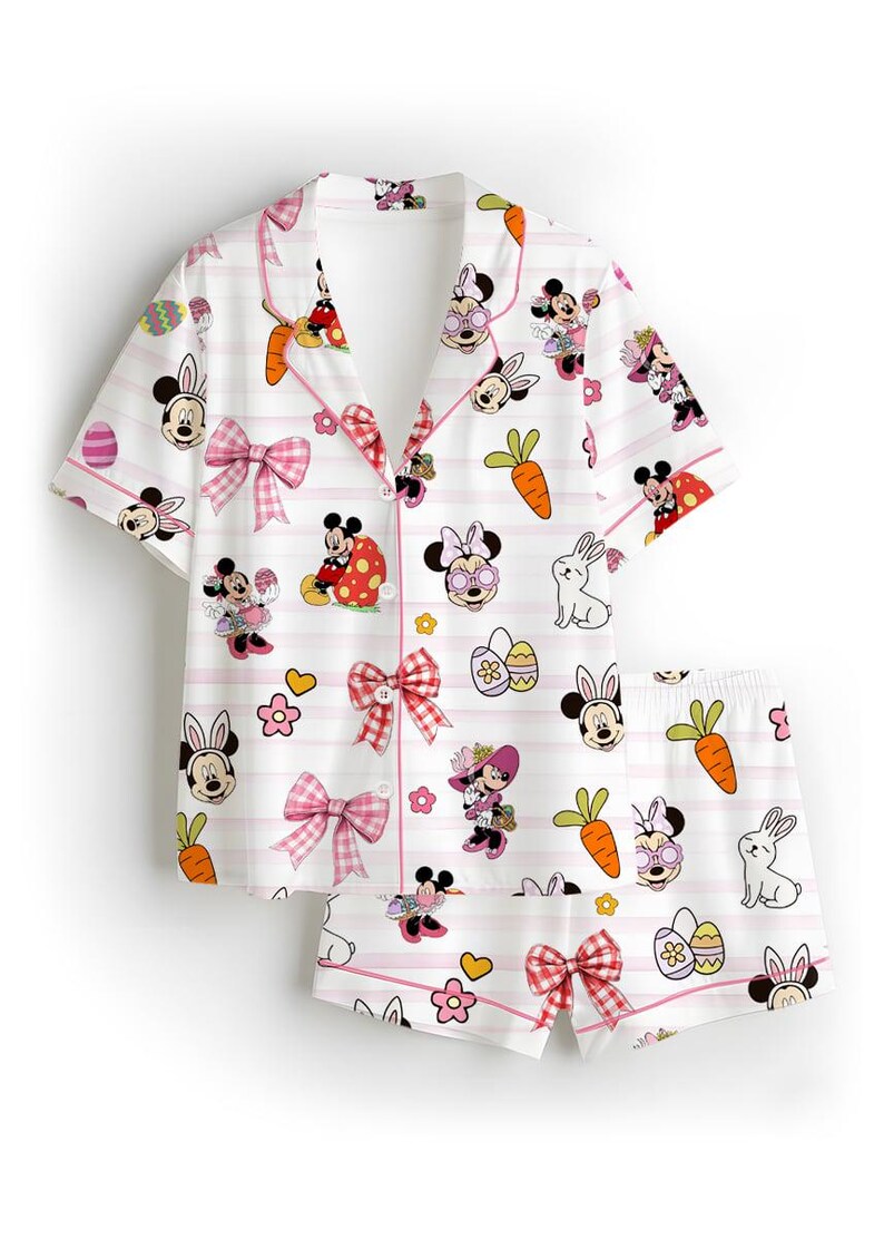 Puede incluir: Conjunto de pijama blanco con estampado de dibujos animados con Minnie Mouse en dise&ntilde;os tem&aacute;ticos de Pascua. El conjunto incluye una camisa con botones y pantalones cortos, ambos adornados con lazos y rayas rosas. Tambi&eacute;n se presentan zanahorias, huevos y flores.