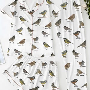 Puede incluir: Conjunto de pijama blanco con estampado de p&aacute;jaros. El conjunto incluye una camisa de manga corta con botones, pantalones cortos y pantalones largos. Cada pieza est&aacute; adornada con ilustraciones de aves y nombres.