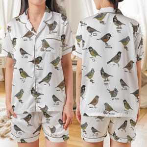 Puede incluir: Conjunto de pijama blanco con estampado de p&aacute;jaros. La parte superior de manga corta y los pantalones cortos presentan varias ilustraciones de p&aacute;jaros con etiquetas. El conjunto tiene una camisa con botones y cuello con solapas y pantalones cortos con cintura el&aacute;stica, ribeteados con un borde marr&oacute;n.