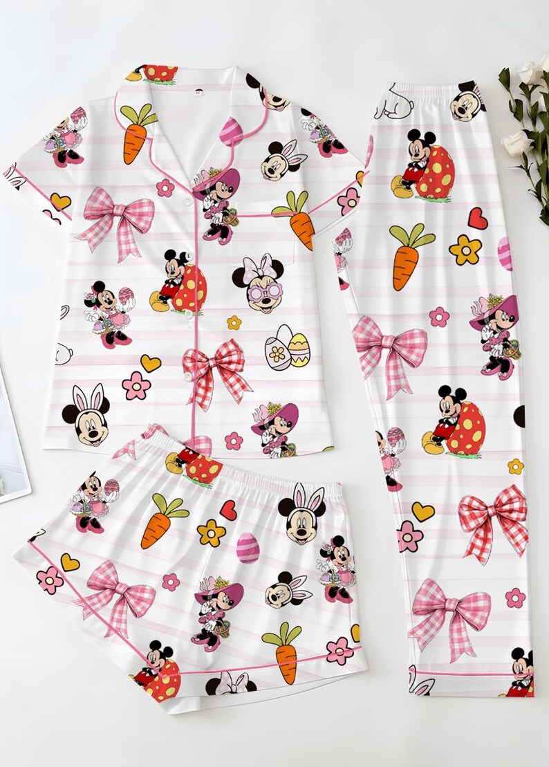 Puede incluir: Un conjunto de pijama de tres piezas con fondo blanco, rayas rosas y dise&ntilde;os de Minnie Mouse. El conjunto incluye una camisa de manga corta, pantalones cortos y pantalones largos, todos adornados con personajes de dibujos animados, zanahorias y lazos.