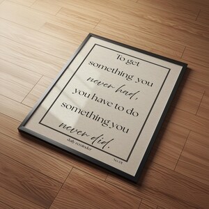 May include: A framed print with the text "To get something you never had, you have to do something you never did." The print has a beige background with black text and a black frame. The words "daily reminder" and "No. 01" are also present.
