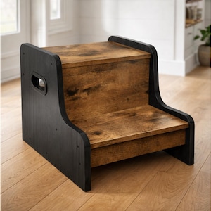 May include: Two-step wooden stool with a black frame and a brown, wood-grain finish on the steps. The stool has a handle cutout on the side for easy portability. The design is suitable for various uses around the home.