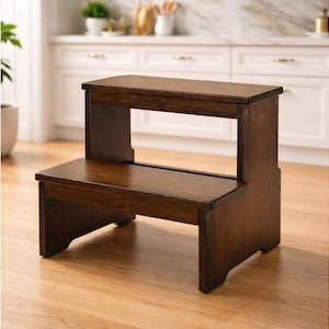 May include: A two-step wooden step stool with a rich, dark brown finish. The stool has a rectangular top step and a lower step, both with a smooth surface. The design is simple and functional, suitable for reaching higher places.