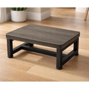 May include: A small, rectangular step stool with a dark wood-grain top and black metal legs. The step stool is designed with a sturdy frame and is suitable for various uses around the home. The dimensions are approximately 15 inches long, 12 inches wide, and 8 inches high.