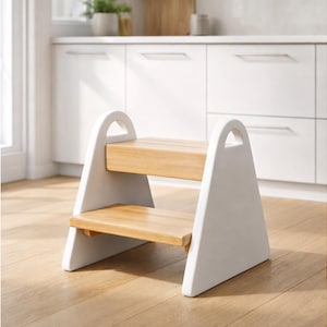 May include: A two-step wooden stool with a white frame and natural wood steps. The stool has a triangular design with arched handles at the top. The steps are made of light-colored wood, and the frame is painted white.