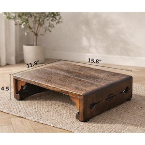 May include: A wooden step stool with a rectangular top and decorative cutouts on the sides. The stool is 15.8 inches long, 11.8 inches wide, and 4.5 inches high. It has a dark brown finish and is placed on a neutral-colored rug.