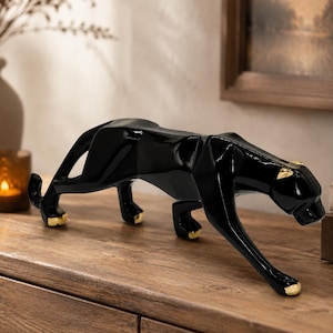 May include: A black panther ornament with gold detailing on the paws and ears. The figurine is in a prowling pose, adding a touch of modern elegance to home decor. The panther is approximately 30 cm long.