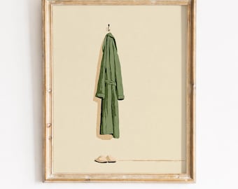 May include: A framed wall art print featuring a sage green bathrobe hanging from a single hook against a solid cream background, with a pair of light beige slippers positioned directly below the robe on the floor level of the illustration.